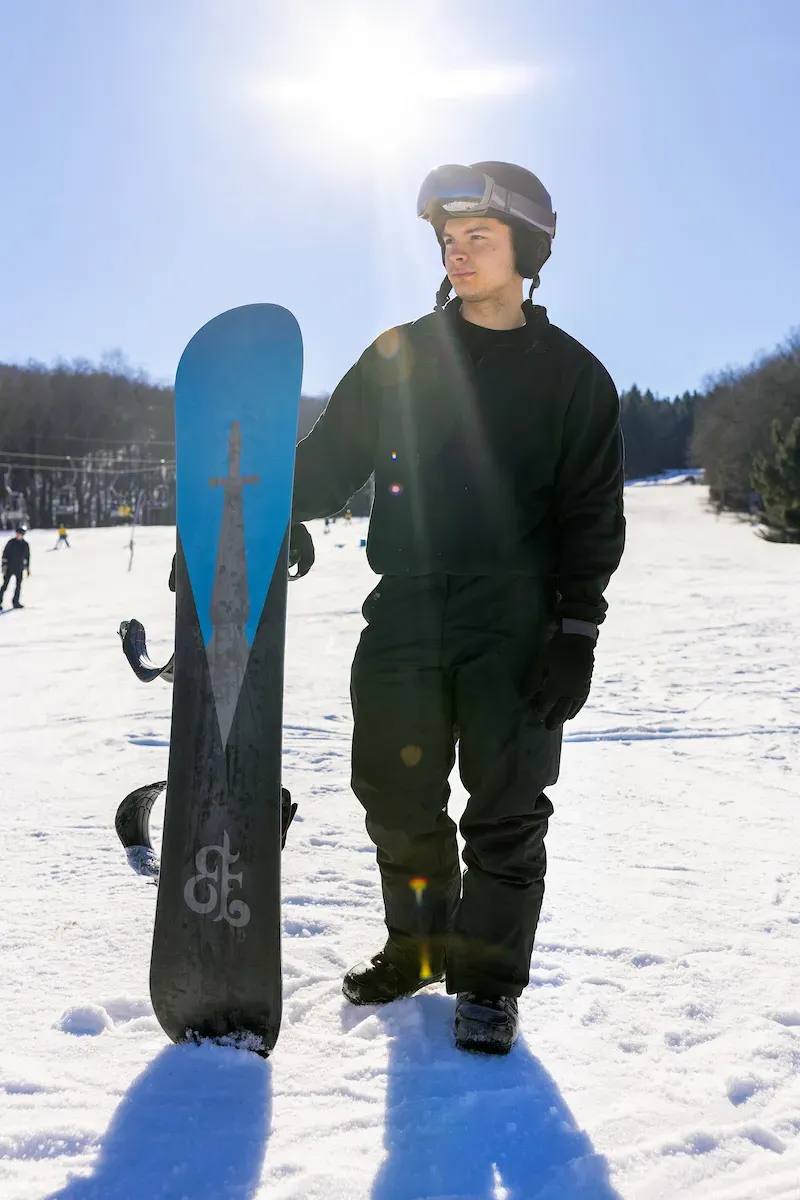 A person holding a snowboard on a hill.